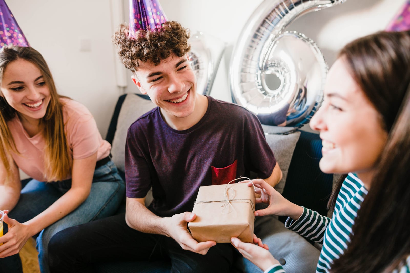 La IA ayuda a decidir, pero el momento de entregar el regalo sigue siendo cosa de personas Grupo de amigos sonriendo mientras se intercambian regalos envueltos en una reunión